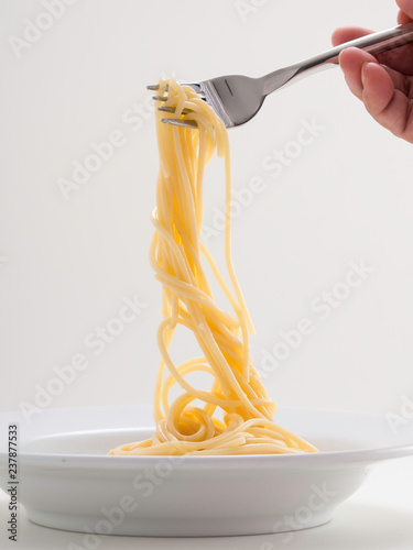 hand holding roll pasta spaghetti with a fork and bish photo