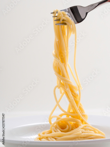 hand holding roll pasta spaghetti with a fork and bish photo