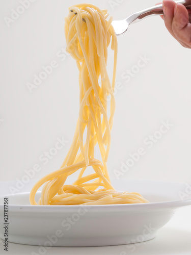 hand holding roll pasta spaghetti with a fork and bish photo