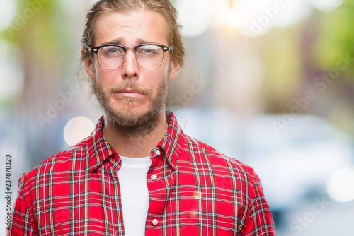 Young handsome man with long hair wearing glasses over isolated background depressed and worry for distress, crying angry and afraid. Sad expression.