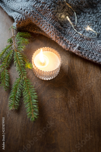 Christmas candles and wool scarf over darkwooden  background with lights
