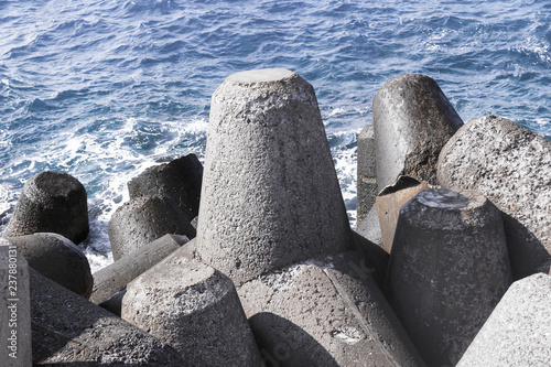 pile of gray breakwaters cement coast guard against the sea large stone triangles powerful weather-beaten