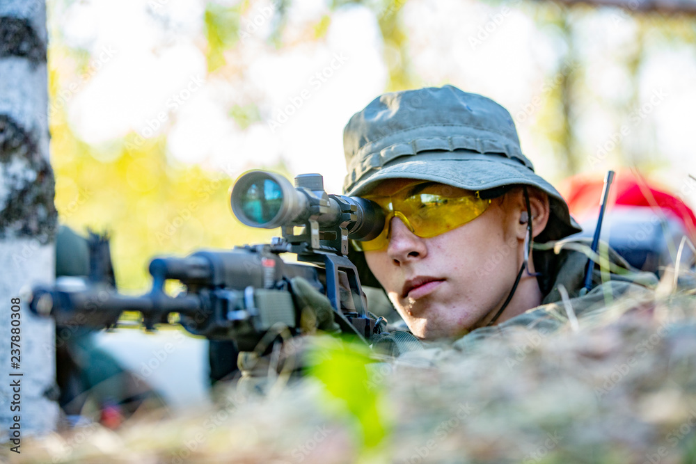 Sniper armed with large caliber, sniper rifle, shooting enemy targets on range from shelter, sitting in ambush Sniper armed with large caliber, sniper rifle, shooting enemy targets on range from shelter, sitting in ambush