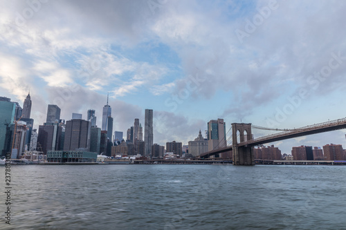 View of Manhattan with Brooklyn Bridge at sunset from the side of the pier. © A_Skorobogatova
