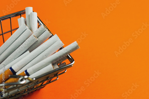 Full market basket of cigarettes with filter on orange background with copy space for your text or logo. Business concept