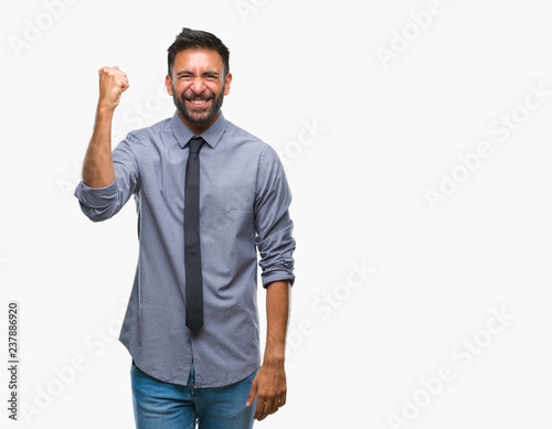 Adult hispanic business man over isolated background angry and mad raising fist frustrated and furious while shouting with anger. Rage and aggressive concept. © Krakenimages.com