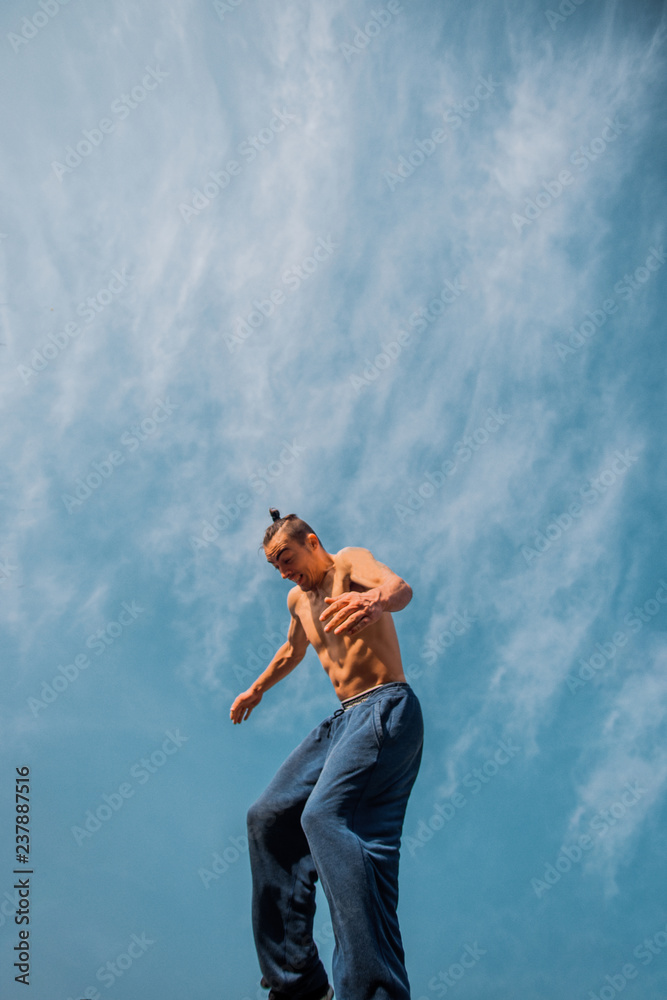 Stuntman trains parkour below blue sky while jumping Stuntman trains parkour below blue sky while jumping
