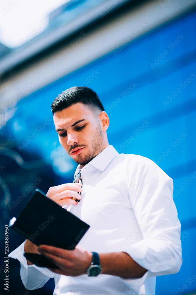 Young businessman is reading his notebook while making plans for the day.