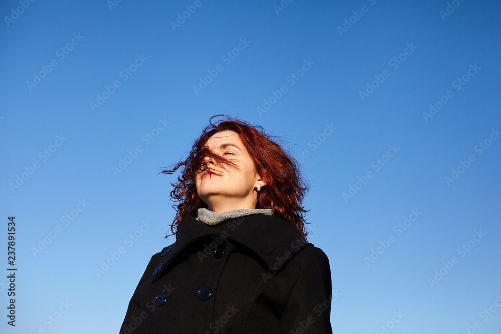 Portrait of pretty woman in warm clothes outdoors with with city background