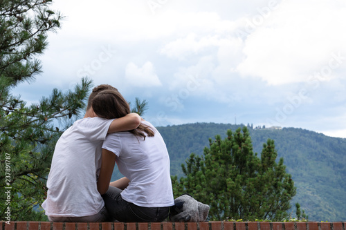 The guy hugs a girl on a background of mountains on the edge of a high-rise building.