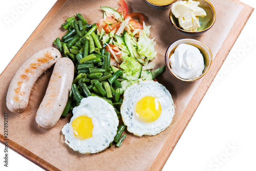 Omelette with sausages and vegetables on wooden cutting board on white background. English breakfast