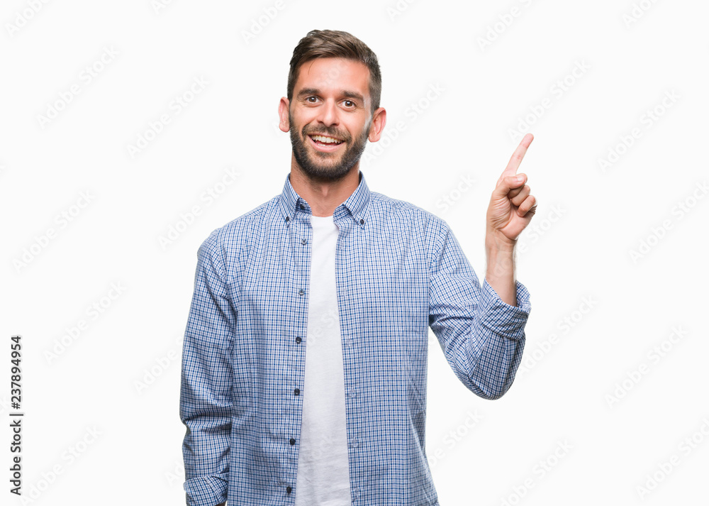 Young handsome man wearing white t-shirt over isolated background with a big smile on face, pointing with hand and finger to the side looking at the camera. Young handsome man wearing white t-shirt over isolated background with a big smile on face, pointing with hand and finger to the side looking at the camera.