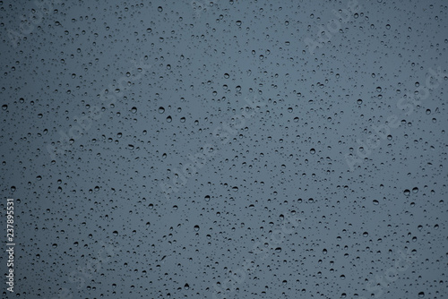 Regentropfen auf einer Fensterscheibe vor grauem Dezembermorgen