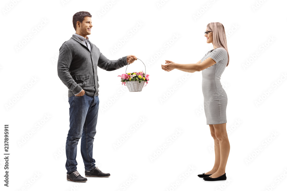 Young man giving a basket with flowers to a young woman