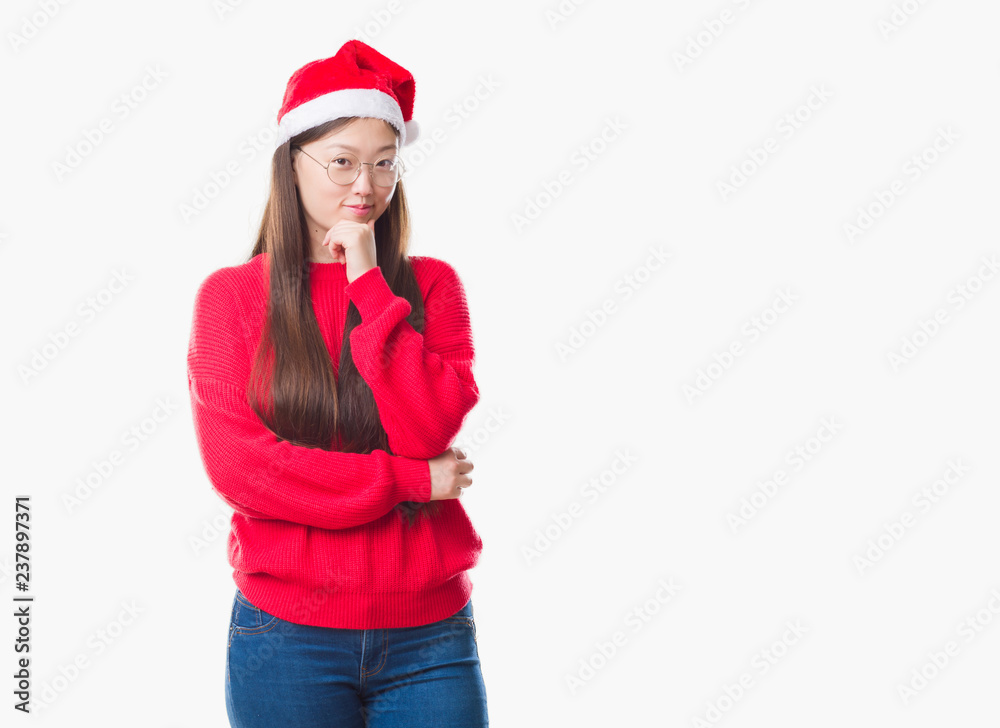Young Chinese woman over isolated background wearing christmas hat looking confident at the camera with smile with crossed arms and hand raised on chin. Thinking positive. Young Chinese woman over isolated background wearing christmas hat looking confident at the camera with smile with crossed arms and hand raised on chin. Thinking positive.