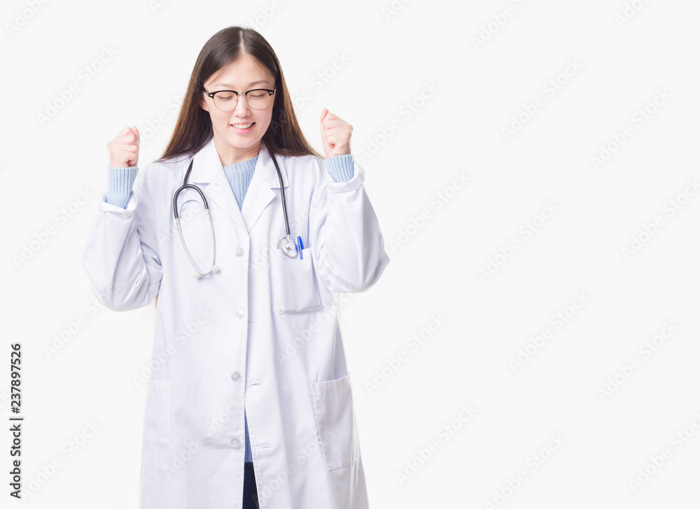 Young Chinese doctor woman over isolated background excited for success with arms raised celebrating victory smiling. Winner concept. Young Chinese doctor woman over isolated background excited for success with arms raised celebrating victory smiling. Winner concept.