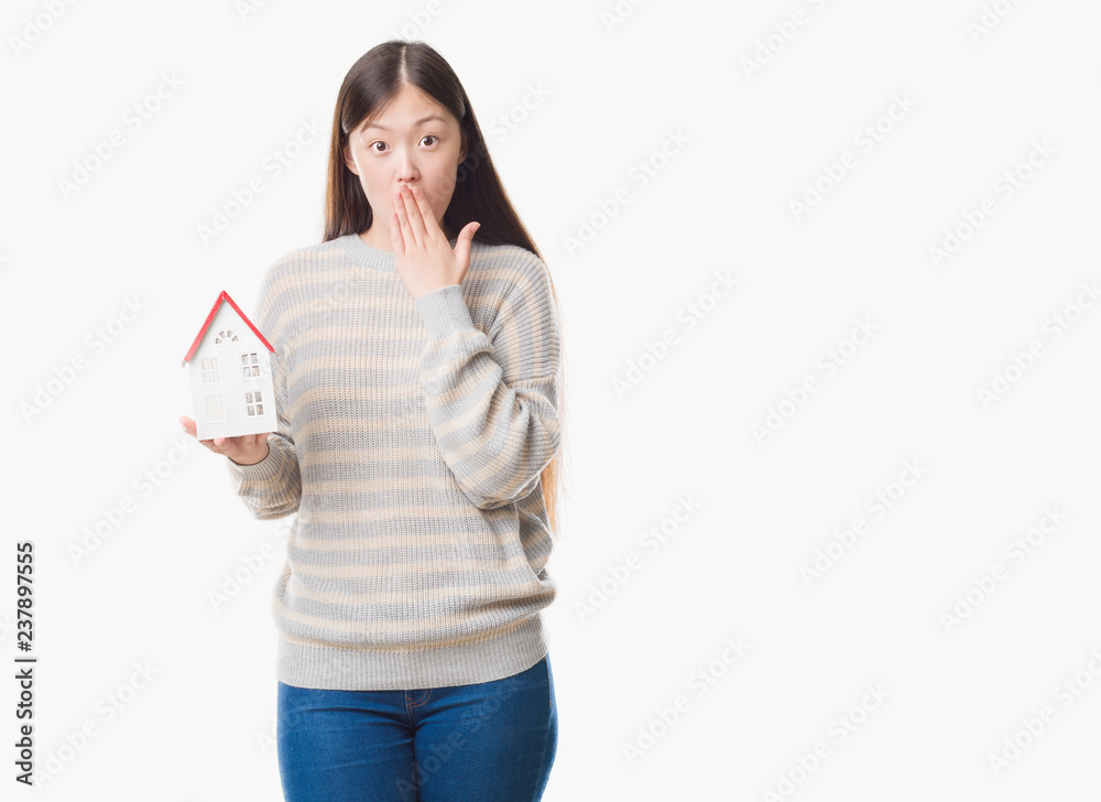 Young Chinese real state agent woman over isolated background holding house cover mouth with hand shocked with shame for mistake, expression of fear, scared in silence, secret concept Young Chinese real state agent woman over isolated background holding house cover mouth with hand shocked with shame for mistake, expression of fear, scared in silence, secret concept