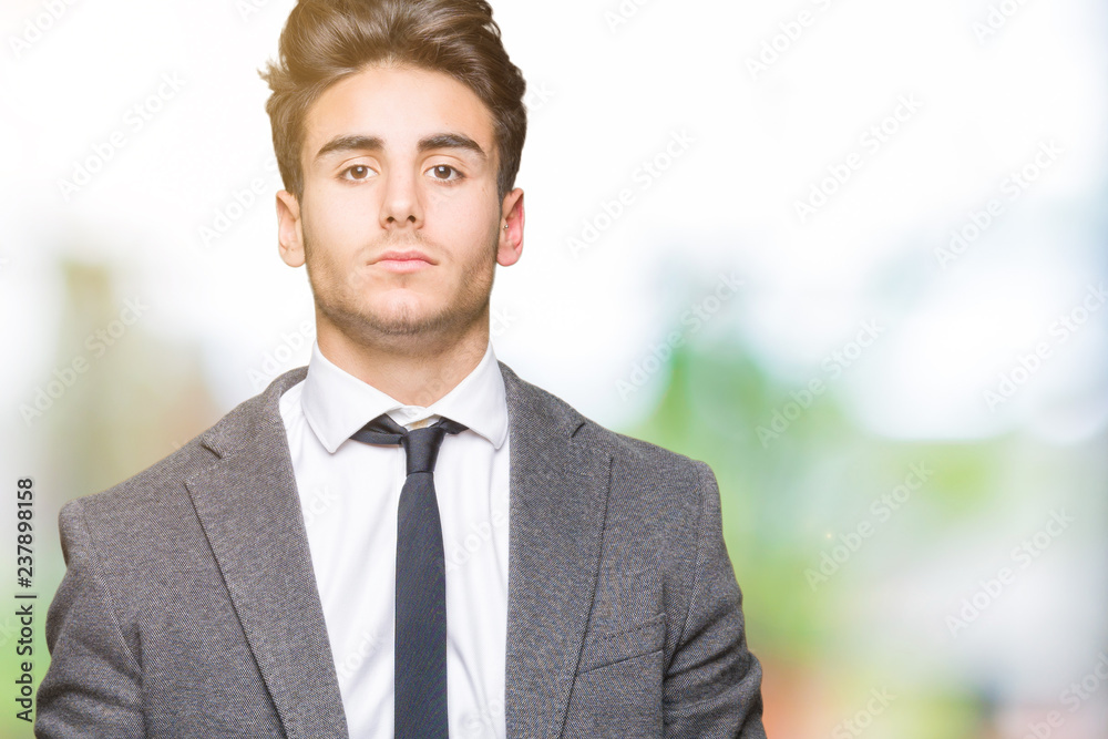 Young business man wearing suit and tie over isolated background with serious expression on face. Simple and natural looking at the camera. Young business man wearing suit and tie over isolated background with serious expression on face. Simple and natural looking at the camera.