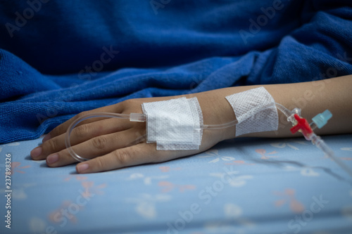 Selective focus Hand of the woman lying on the bed with IV line on hand in the patient room at the hospital.