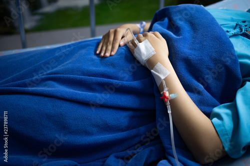 Sick woman having a stomachache and receiving intravenous fluid through IV line at the hospital.