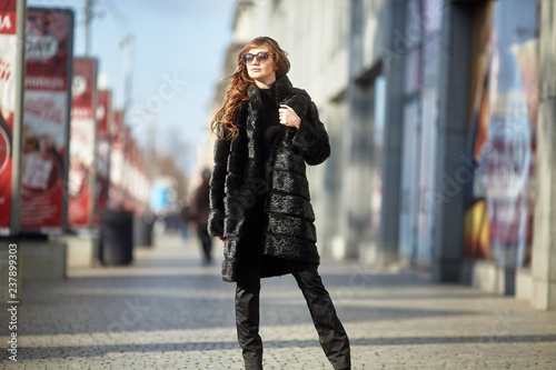 The girl walks through the city in a fur coat © Shchepin