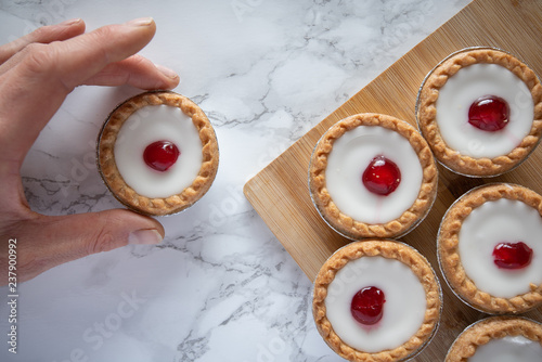 Delicious baked tarts cakes top down flat lay shot mans hand takes cake marble background photo