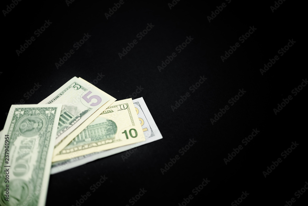 Dollars on dark black abstract background. Horizontal top view, several objects. One hundred dollars Dollars on dark black abstract background. Horizontal top view, several objects. One hundred dollars