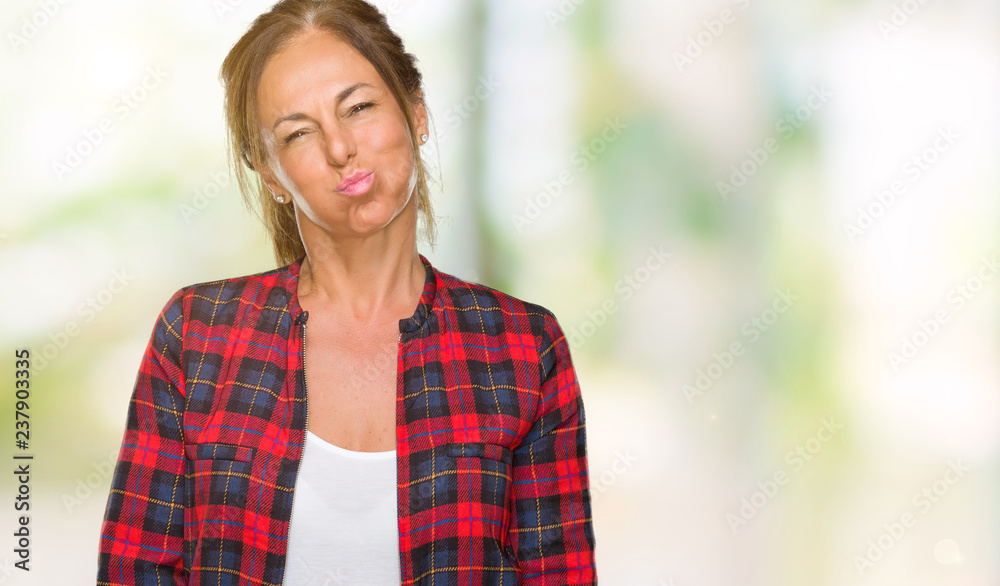 Middle age adult woman wearing casual jacket over isolated background puffing cheeks with funny face. Mouth inflated with air, crazy expression.
