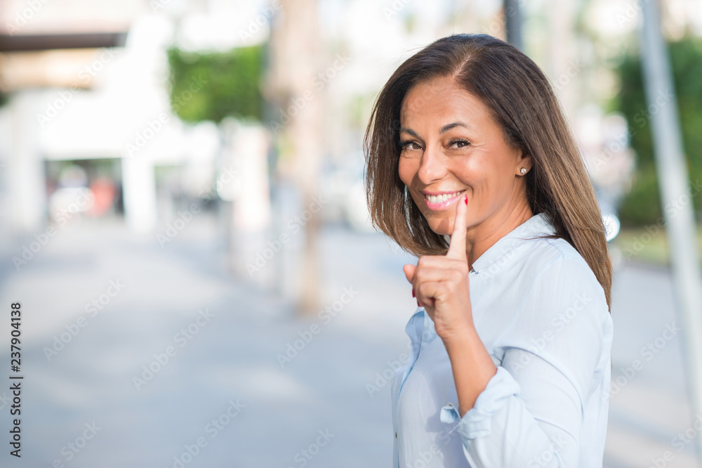 Beautiful middle age hispanic woman at the city street on a sunny day surprised with an idea or question pointing finger with happy face, number one Beautiful middle age hispanic woman at the city street on a sunny day surprised with an idea or question pointing finger with happy face, number one