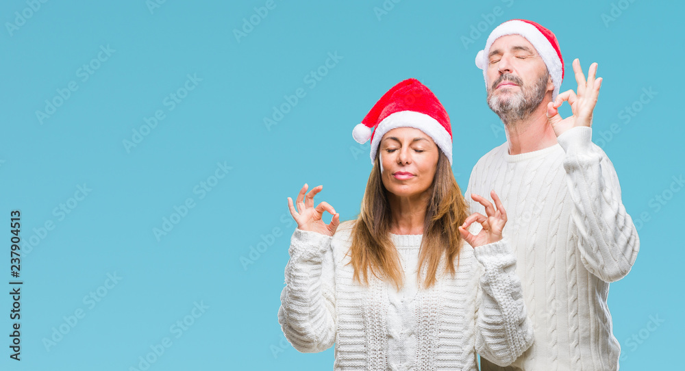Obraz premium Middle age hispanic couple wearing christmas hat over isolated background relax and smiling with eyes closed doing meditation gesture with fingers. Yoga concept.