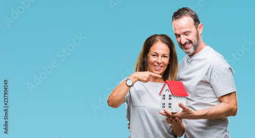 Middle age hispanic casual couple buying new house over isolated background very happy pointing with hand and finger