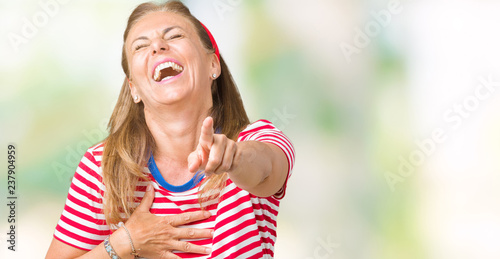 Beautiful middle age woman wearing casual stripes t-shirt over isolated background Laughing of you, pointing to the camera with finger hand over chest, shame expression