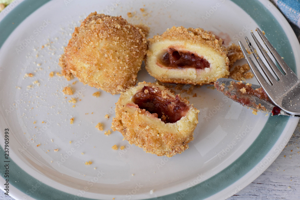 Plum dumplings Knedle on the white plate on the wooden table