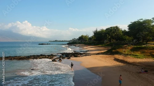 Aerial dolly style shot from behind volcanic rock to reveal Kamaole III Beach.  Maui, Hawaii. photo