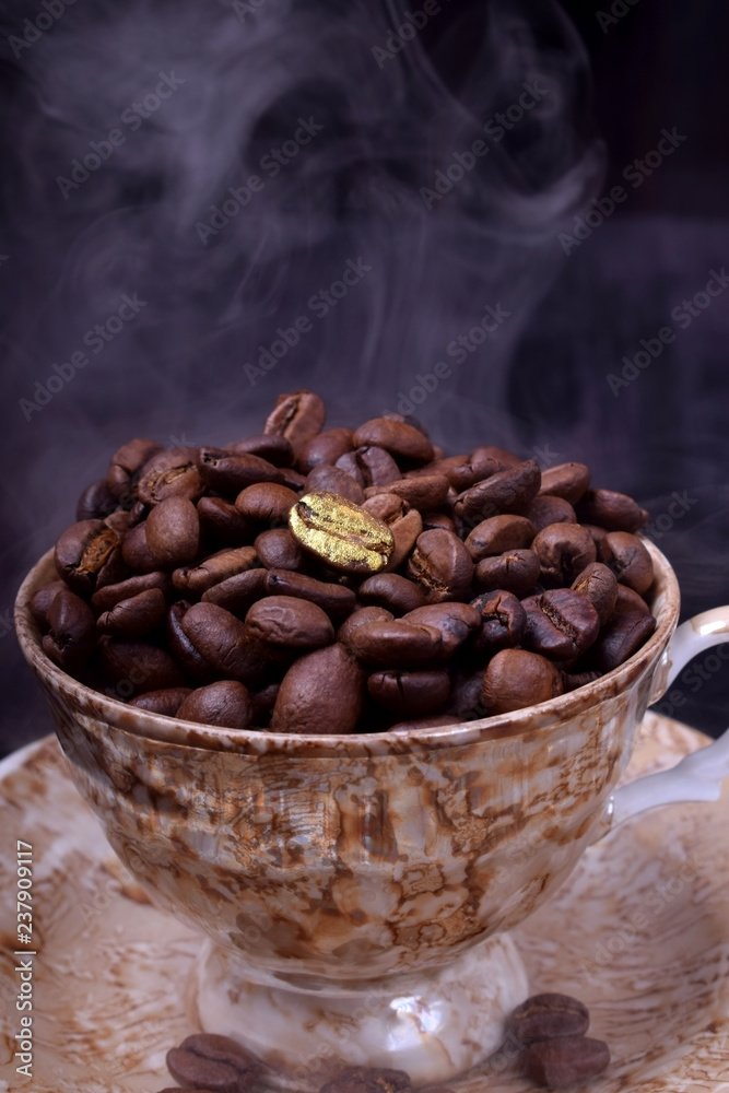 Fototapeta premium Golden coffee bean on freshly roasted ones in a cup against the dark background