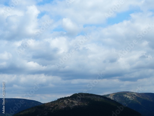Tops of mountains against the sky with white clouds