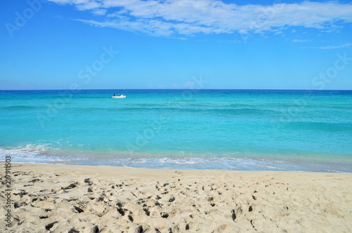 coastline of the ocean, small waves, horizon, endless distance, white motor boat with silhouettes of people in the ocean