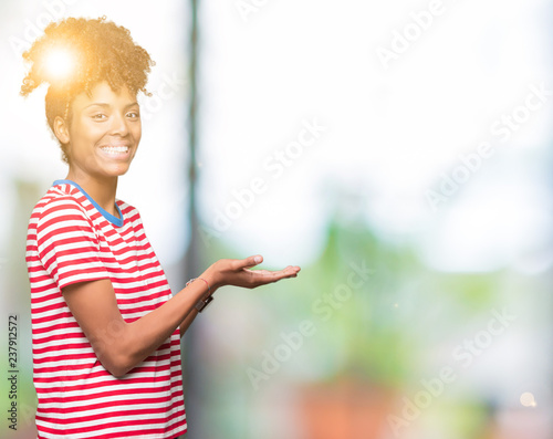Beautiful young african american woman over isolated background Pointing to the side with hand and open palm, presenting ad smiling happy and confident