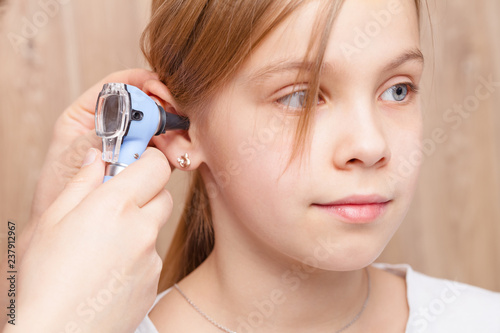 Child ENT check - doctor examining ear of elementary age girl with otoscope