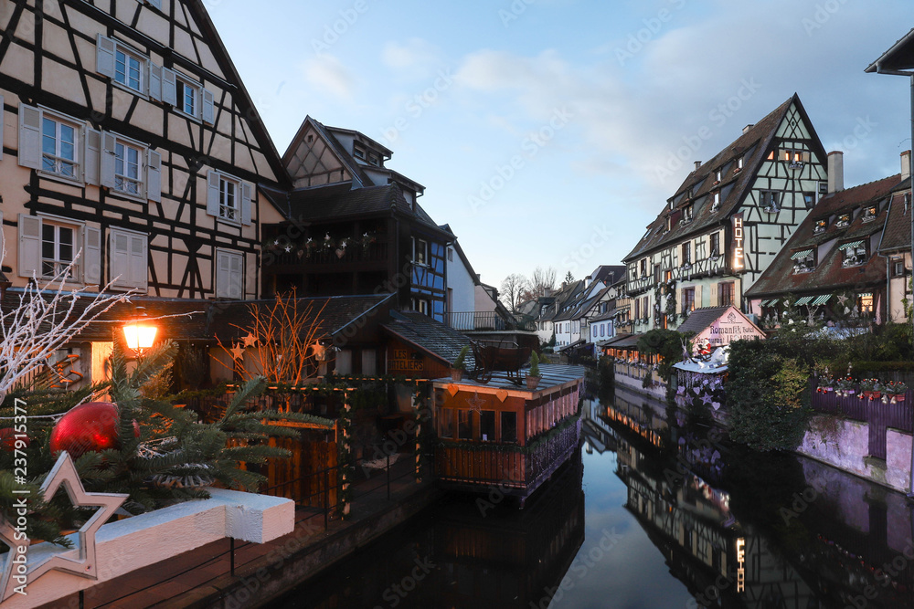 Traditional Alsatian half-timbered houses in old town of Colmar and branches of Christmas tree in the foreground.