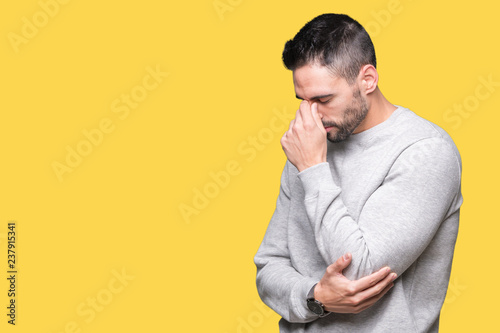 Young handsome man wearing sweatshirt over isolated background tired rubbing nose and eyes feeling fatigue and headache. Stress and frustration concept. © Krakenimages.com