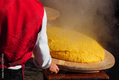 Freshly cooked polenta, still steaming overturned on the appropriate wooden cutting board, according to the tradition of north east Italy 
