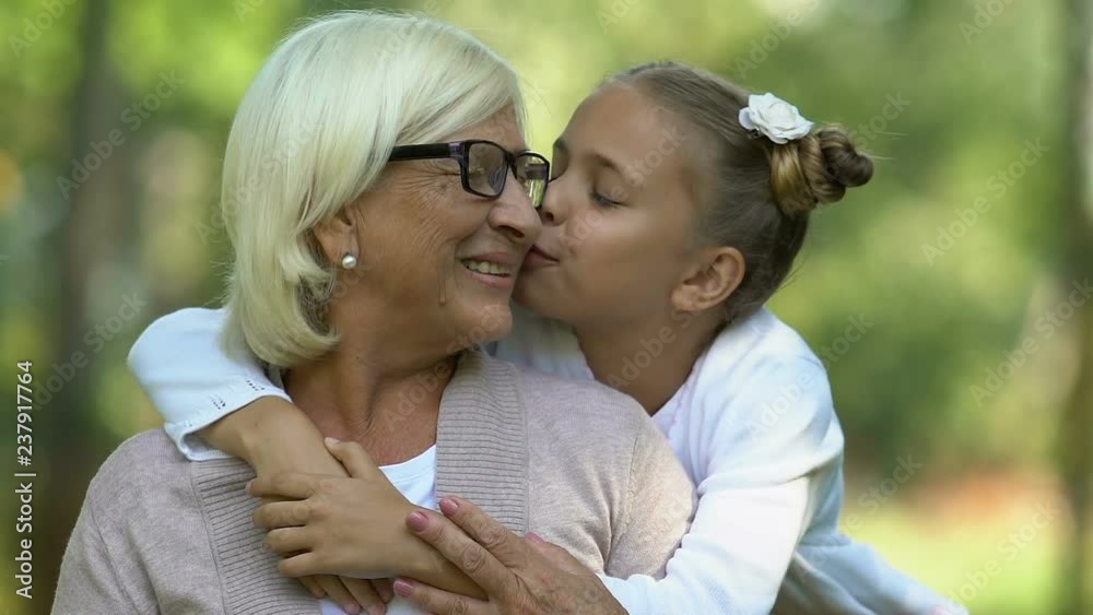 Little beautiful girl hugging and kissing her old grandmother, lovely family Little beautiful girl hugging and kissing her old grandmother, lovely family