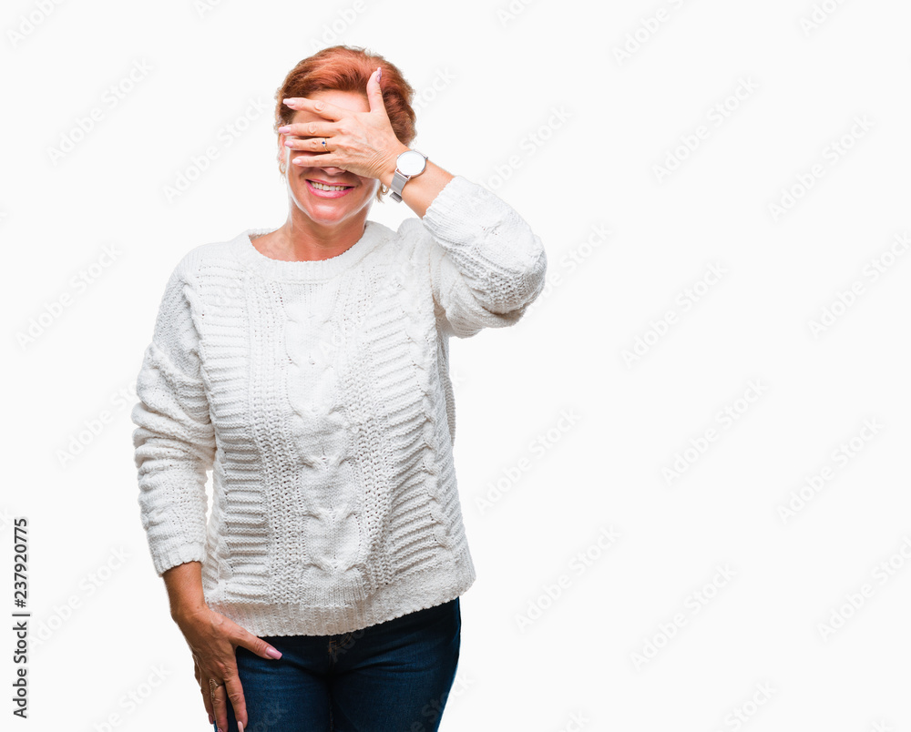 Atrractive senior caucasian redhead woman wearing winter sweater over isolated background smiling and laughing with hand on face covering eyes for surprise. Blind concept. Atrractive senior caucasian redhead woman wearing winter sweater over isolated background smiling and laughing with hand on face covering eyes for surprise. Blind concept.