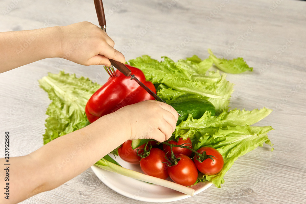 The child cuts vegetables with a knife The child cuts vegetables with a knife
