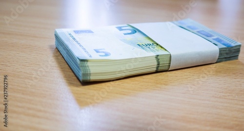 Stack of 5 Euro notes on a pine desk