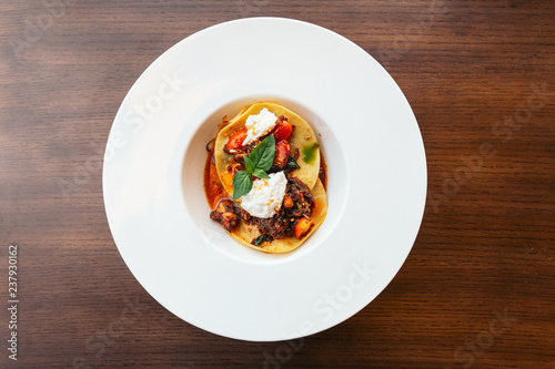 Ravioli with ricotta cheese and tomato served in white plate.