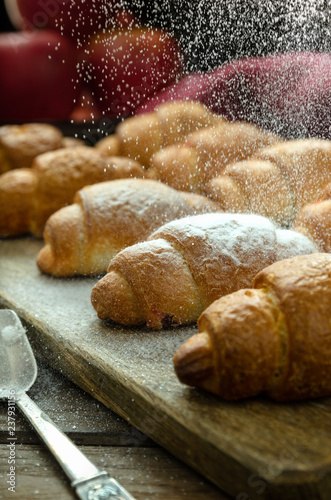 Croissants on a wooden stand sprinkle with powdered sugar.
