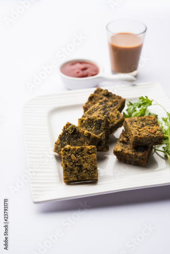 A savory cilantro cake or kothimbir vadi in square shape which is first steamed and then fried until crisp. popular indian snack served with hot tea and tomato ketchup