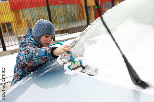 Child brushing snow off car